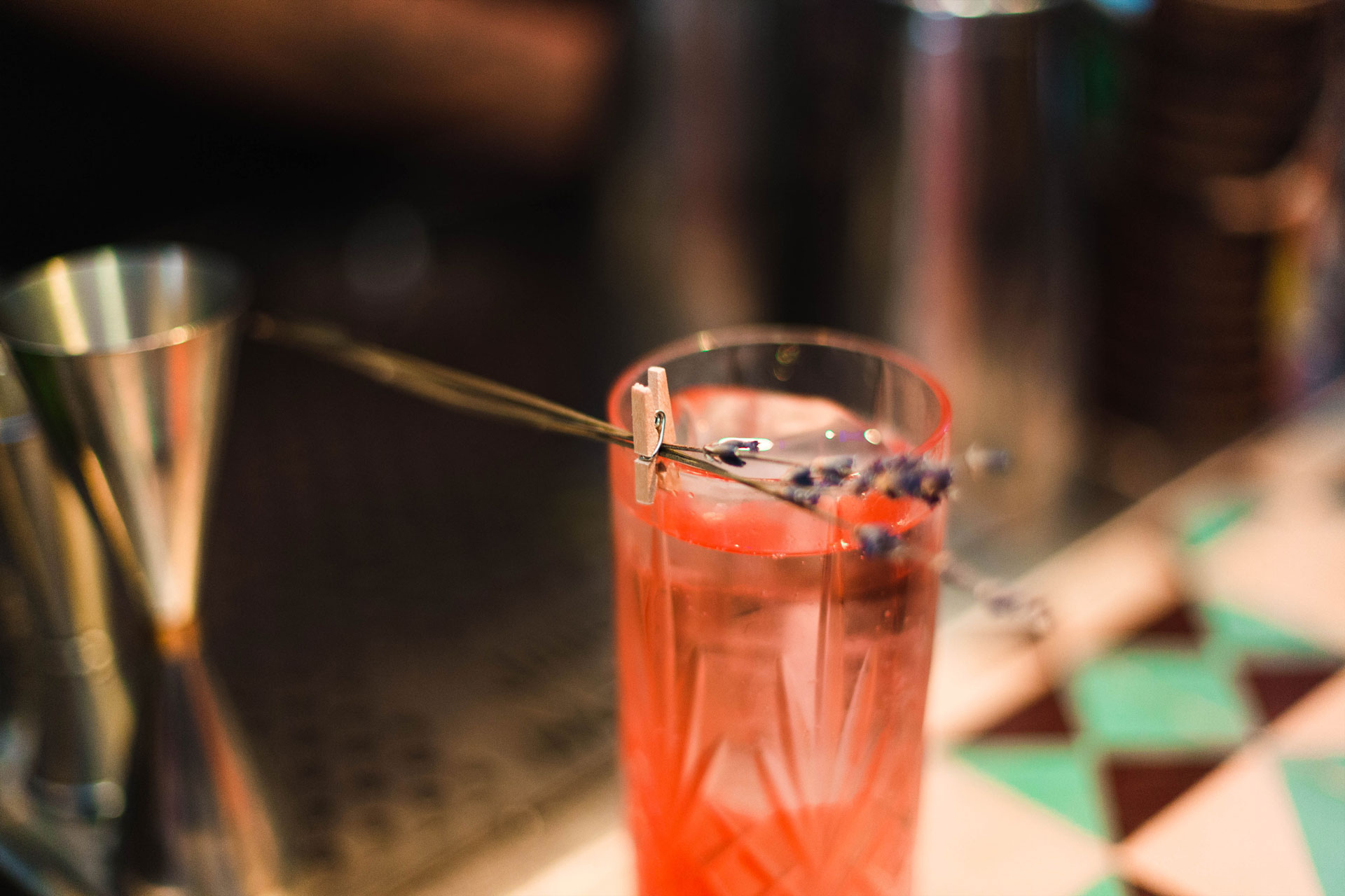 un vaso con coctel rosado y detalle decorativo de flores