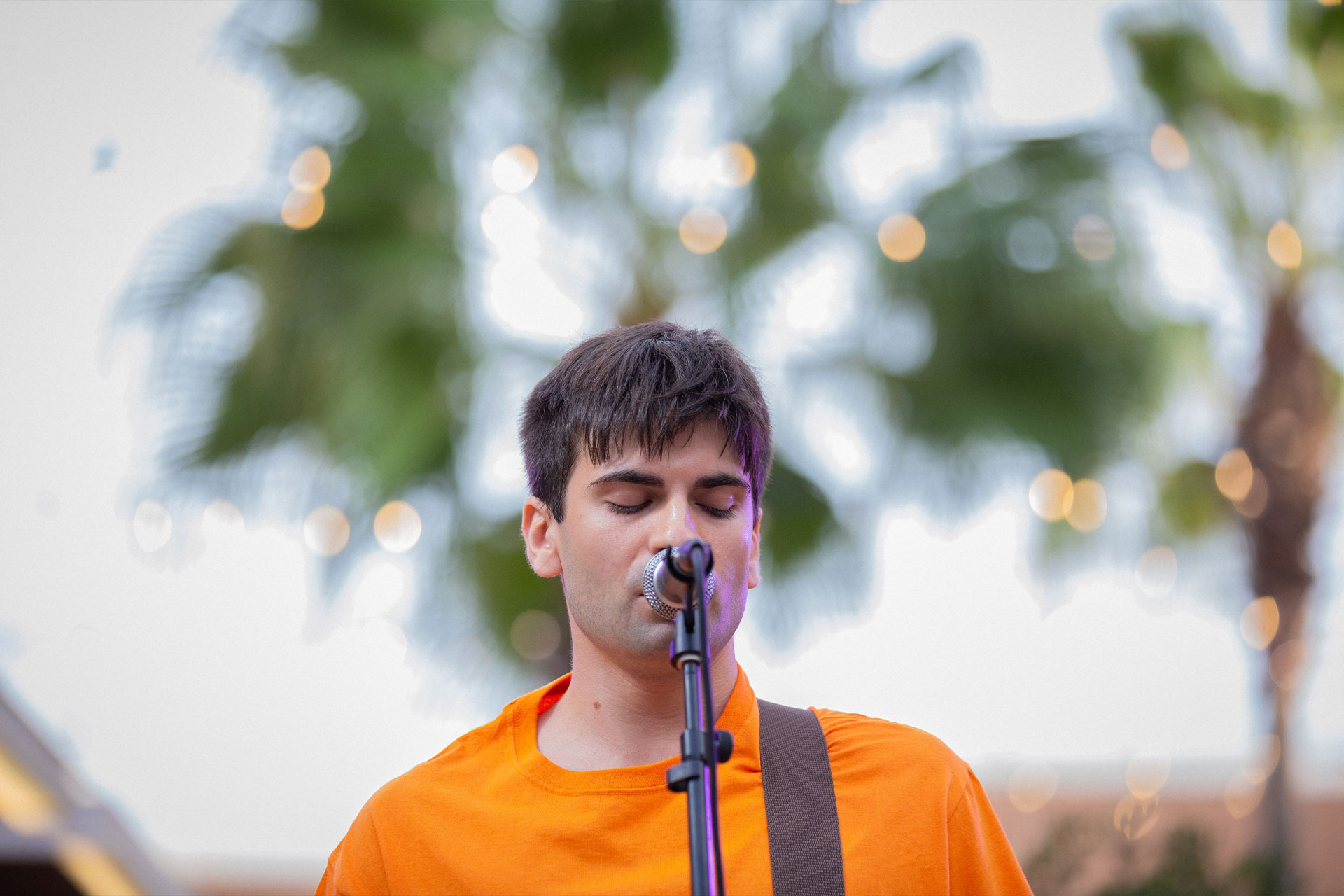 chico joven mirando hacia abajo mientras canta en un microfono
