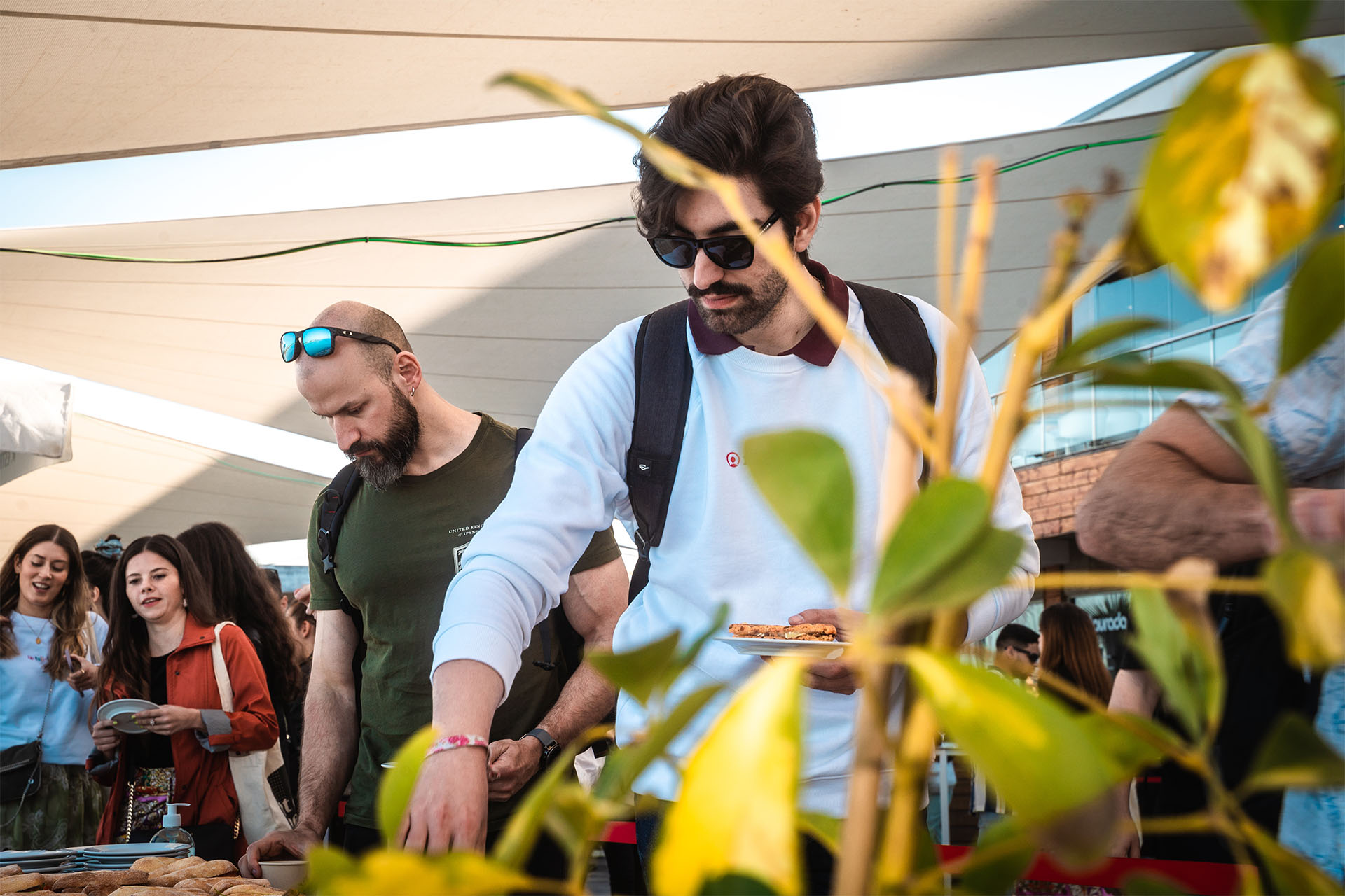 hombre joven con gafas tapado por una planta sirviendose comida