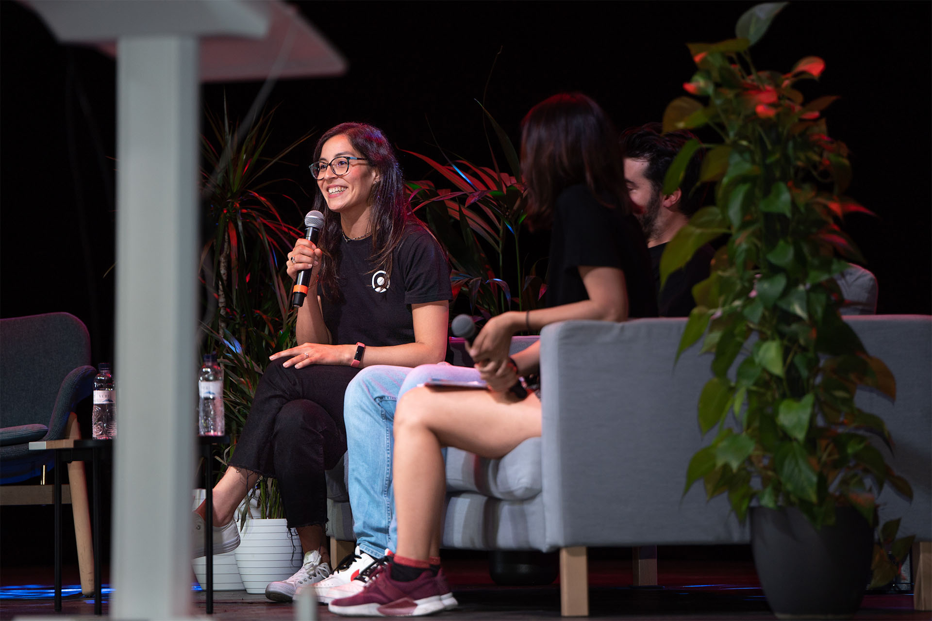 mujer hablando al microfono en un evento y sonriendo